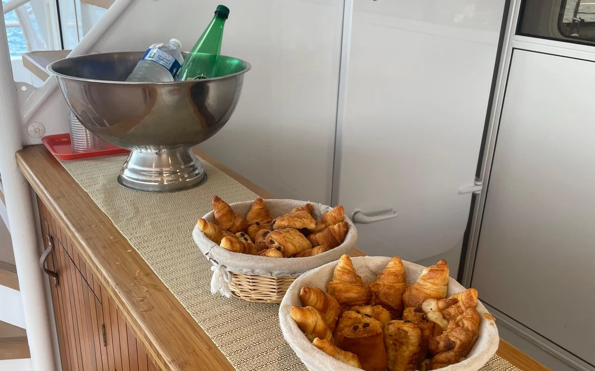Baskets of croissants and an ice bucket with bottles of water on a counter on board