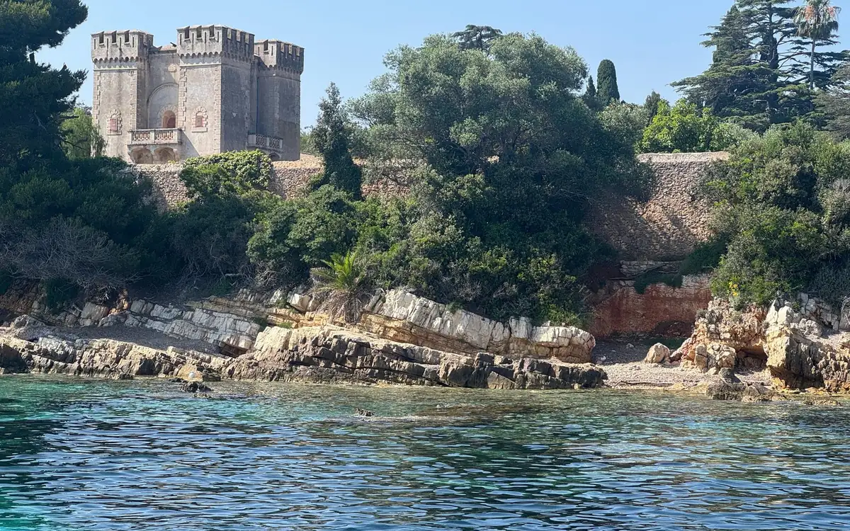 A crenellated stone tower above pale rocks and clear green water