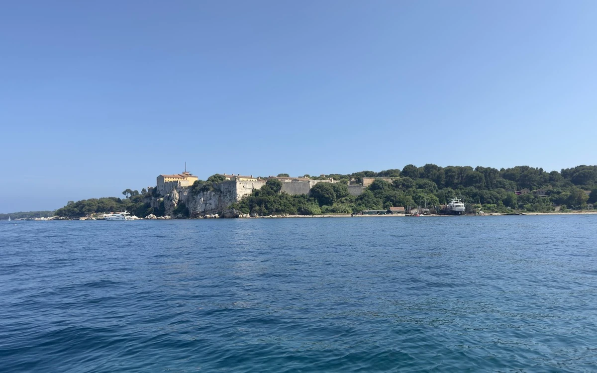 A fort on a low wooded island, seen across open blue water