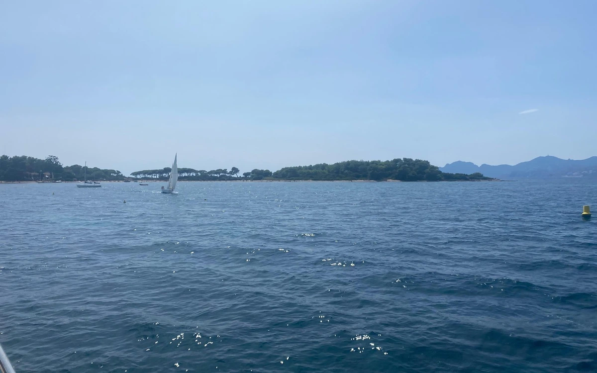 The low green line of the Lérins Islands seen across the sea from a boat deck