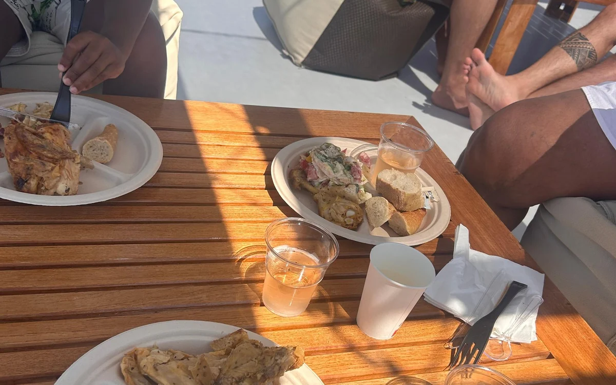 Plates of chicken and bread with cups of a pink drink on a teak table