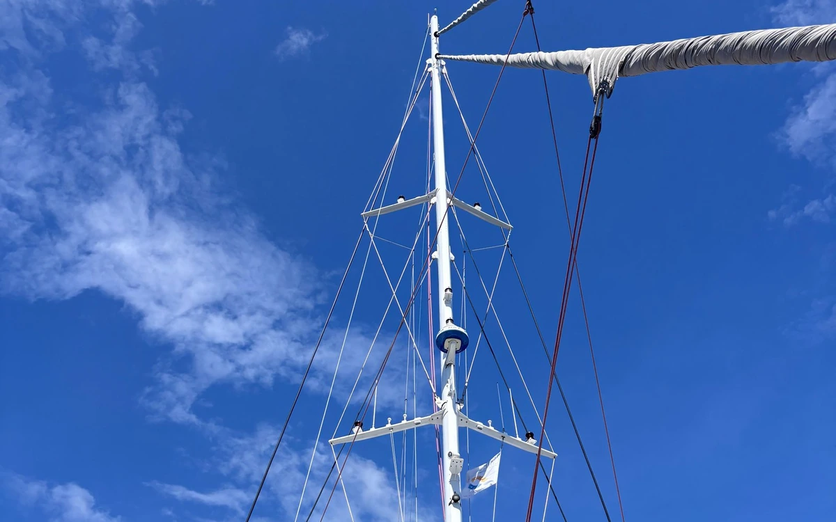 The white mast and rigging of a catamaran against a blue sky