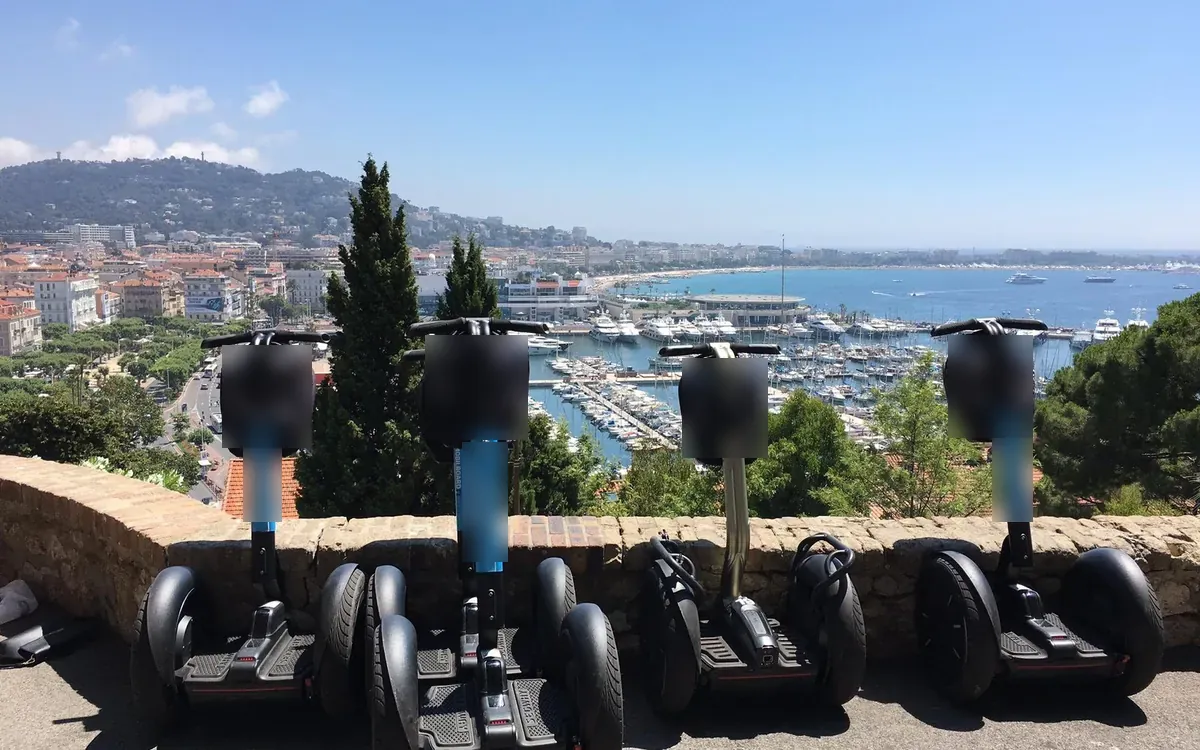 Four self-balancing two-wheelers lined up on a stone wall above the port and its yachts
