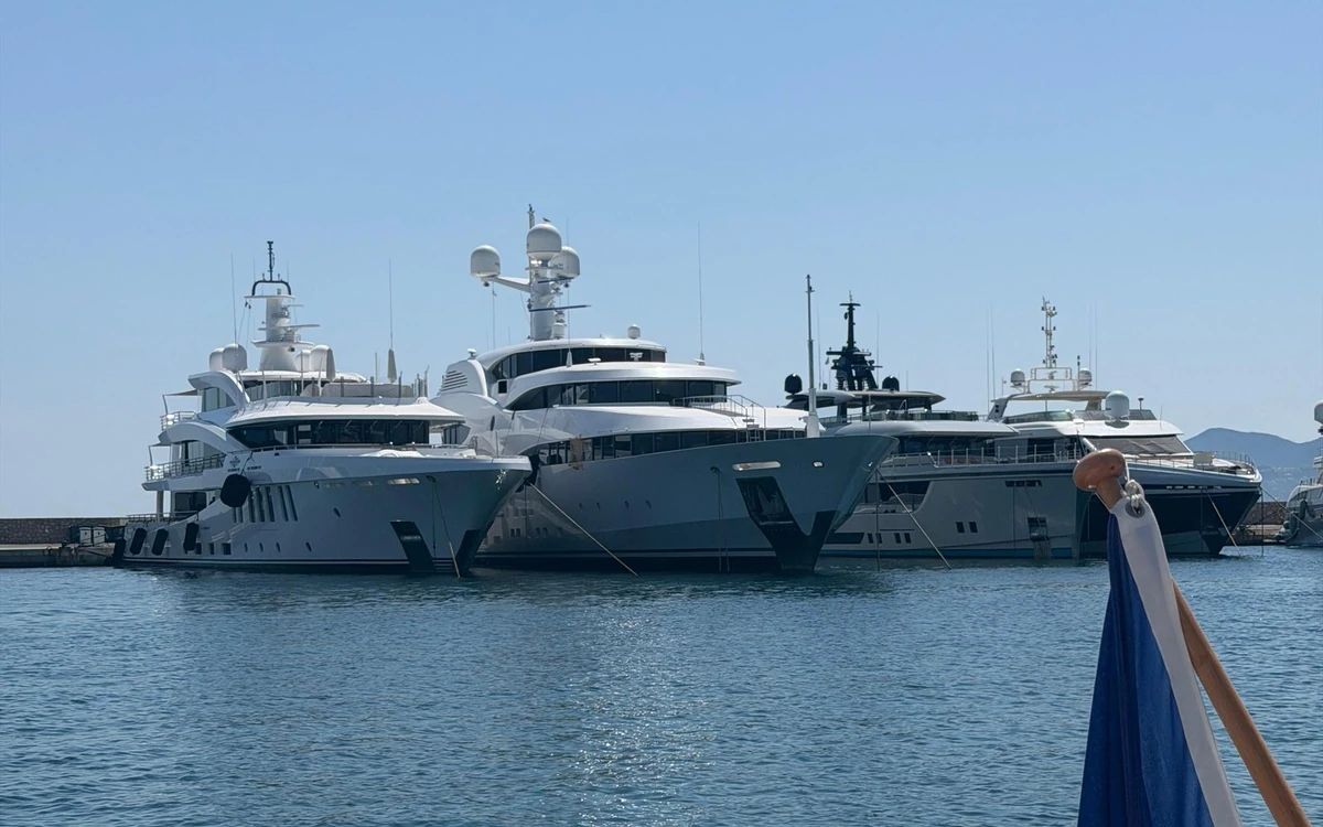 Four large white motor yachts moored side by side in a port